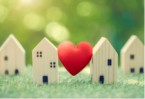 two wooden small toy homes with heart in between