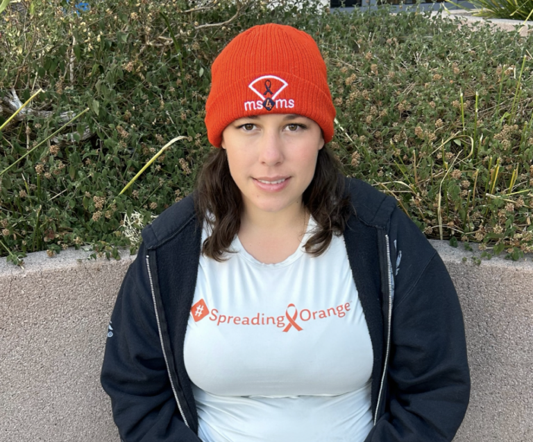 Portrait of Melinda Livermont, who is wearing a bright orange beanie hat and a blue zip-up sweatshirt.