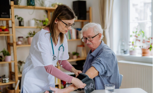 Nurse doing a home visit and taking blood pressure of an older man.