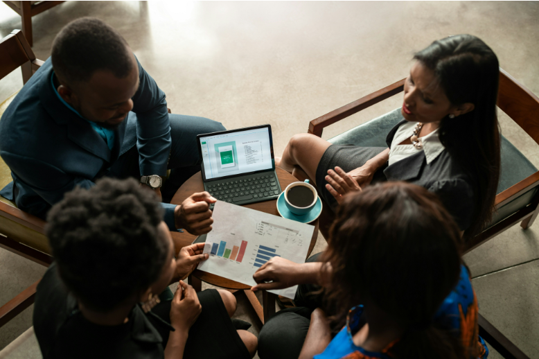 A small group of research professionals sitting around a table looking at a laptop and data.