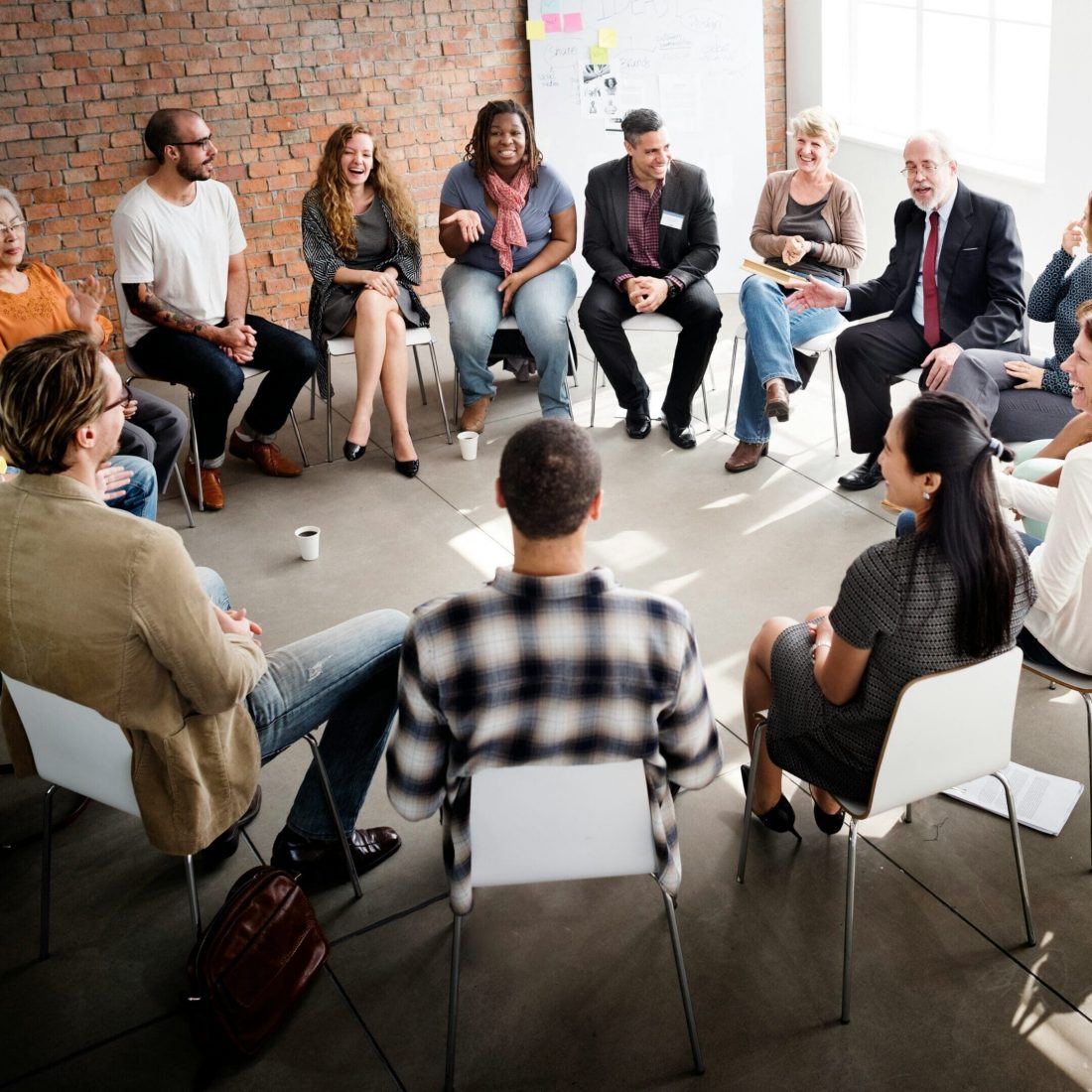 A group of diverse men and women sitting in. a circle having a conversation